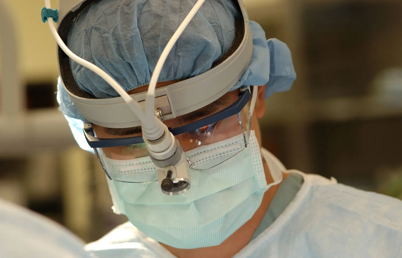 A clinician in surgical loupes and mask during an operative procedure.